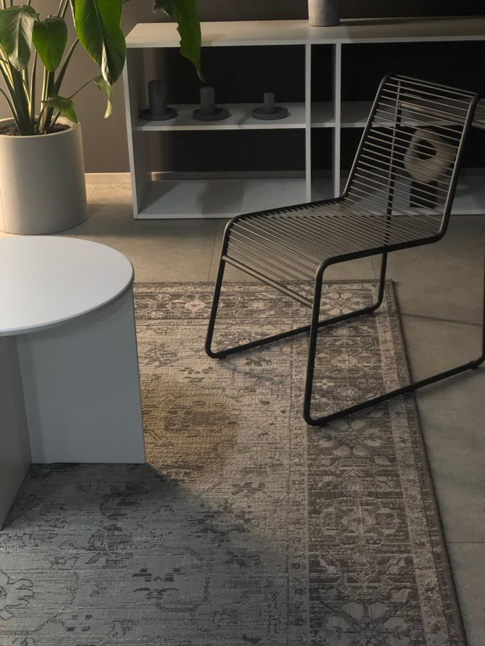 Stylish living room featuring a metal chair, round coffee table, and decorative rug in a modern setting.